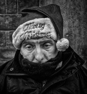 Street photography of a man donning a festive santa hat and scarf.