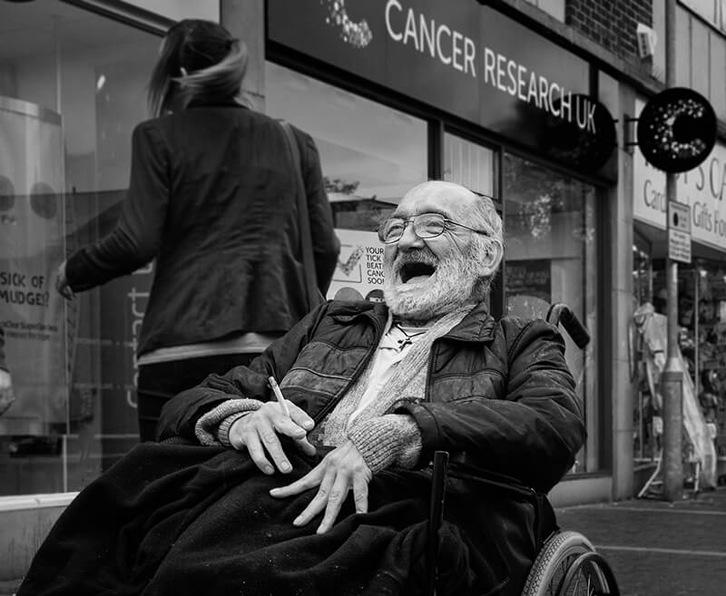 Disabled man smoking in front of Cancer Research