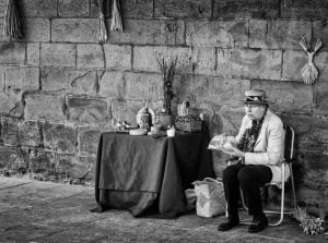 A woman sits at a table, representing street photography.