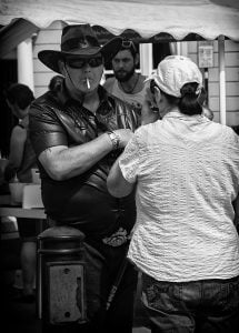 Street photography of a man in a cowboy hat conversing with a woman.