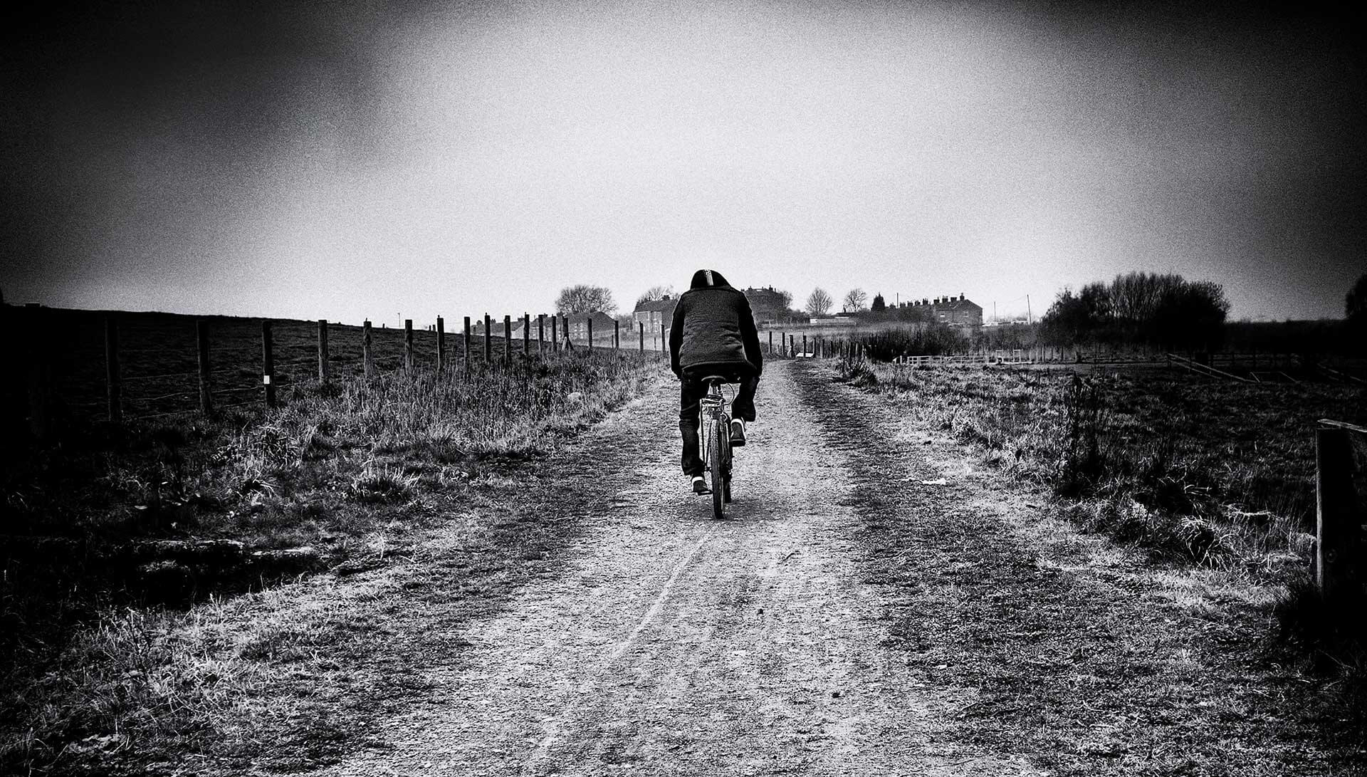 A person riding a bike on a dirt road captured in street photography.