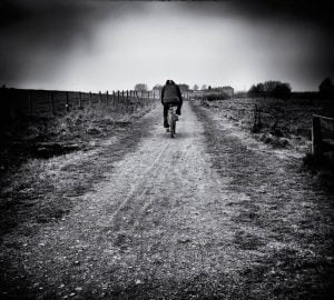 A person riding a bike down a dirt road.