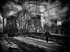 A monochrome street photography showcasing a man strolling along a road with power lines as the backdrop.