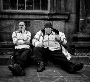 Street photographers capturing two men on steps.