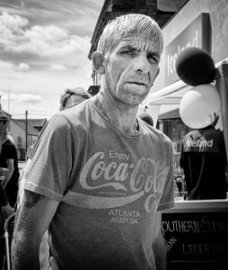 Street photography captures a man in front of a Coca-Cola sign.