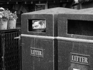 Street photography featuring two trash cans with a picture of a man in them.