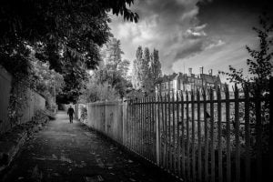 Street photography: A monochrome image capturing a person strolling along a pathway.