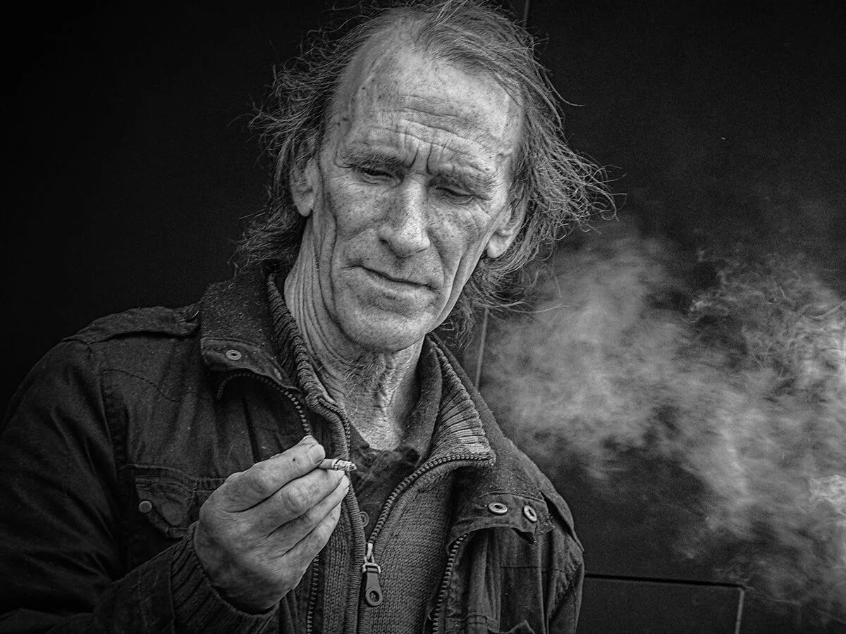 Street photography of a man smoking a cigarette.