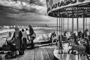 A street photography captured in black and white featuring a carousel on the beach.