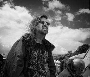 A man with long hair captured in a black and white street photograph.