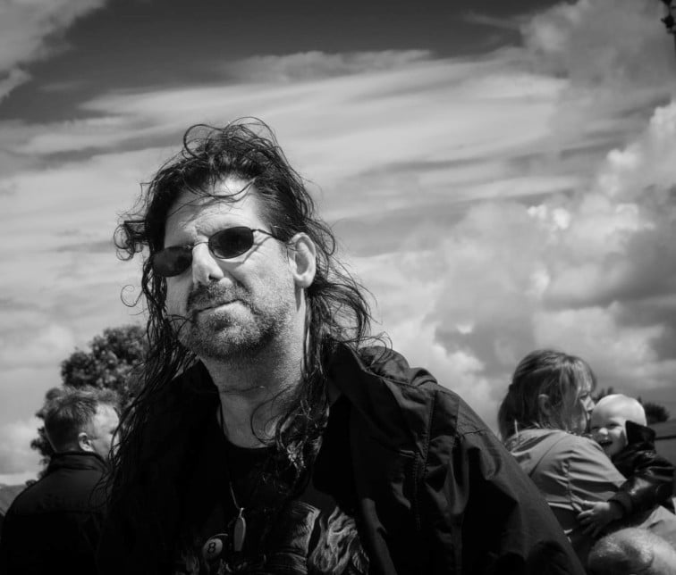A street photography portrait capturing a man with long hair in black and white.