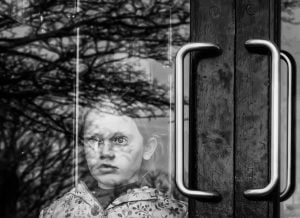 A monochromatic street photography capturing a girl by a door.