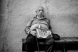 Street photography: A man sitting on a bench in public.