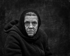 A street photography capturing the essence of an old woman in a black and white photo.