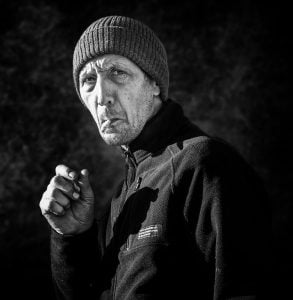 A street photography capturing a man smoking a cigarette in black and white.