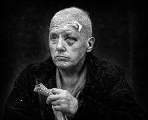 A street photography capturing an old man smoking a cigarette in black and white.