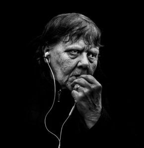 Street photography: A monochrome image capturing an elderly woman engrossed in music.
