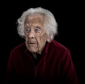 An old woman is sitting on a dark street.