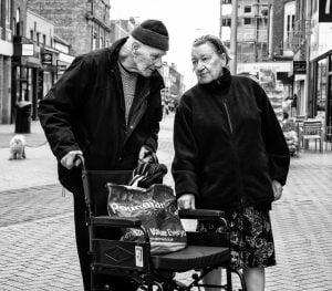 Street photography: A black and white photograph of an elderly couple in a wheelchair captured candidly on the streets.