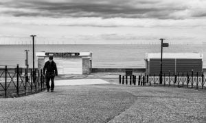Street photography: Black and white photograph of a man walking down a path captures the essence of urban life.