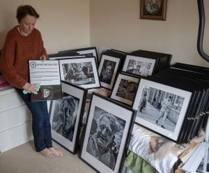 A woman curating a collection of black and white street photography in a room full of framed pictures.