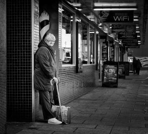 Black and white street photography of a man leaning against a wall.
