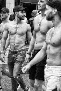 A candid street photography shot capturing a group of shirtless men.