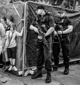 Street photography featuring a group of police officers standing in front of a fence.