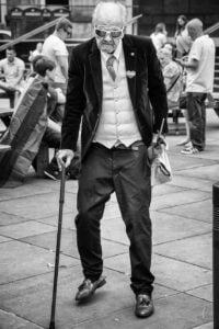 An old man with a cane walking down the street during Leeds Pride 2019.