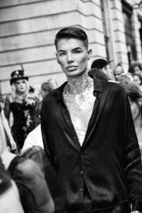 A black and white photo of a man walking down the street at Leeds Pride 2019.