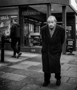 Street photography of an elderly man strolling down the road.