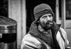 A street photography black and white photo of a man smoking a cigarette.